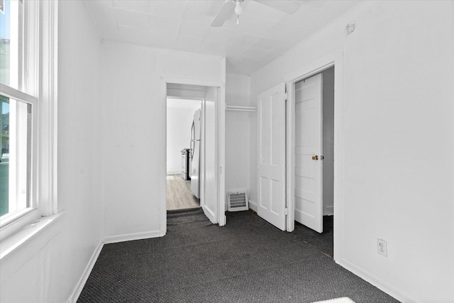 unfurnished bedroom featuring ceiling fan, a closet, white fridge, and dark colored carpet