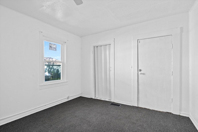 unfurnished bedroom with dark colored carpet, a textured ceiling, and ceiling fan