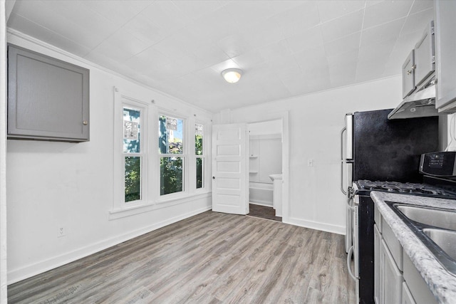 kitchen featuring light wood-type flooring, gray cabinetry, extractor fan, crown molding, and stainless steel range with gas stovetop