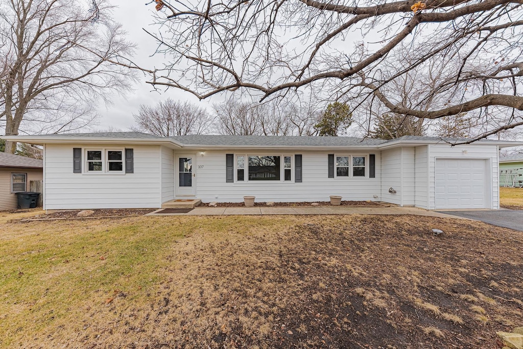 ranch-style home featuring a garage and a front lawn