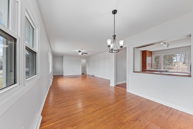 unfurnished living room featuring ceiling fan with notable chandelier and light hardwood / wood-style floors