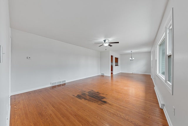 empty room with hardwood / wood-style flooring and ceiling fan with notable chandelier