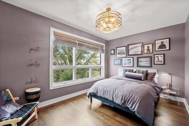 bedroom with dark wood-type flooring and an inviting chandelier