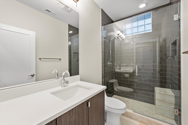 bathroom with vanity, a shower with shower door, and toilet