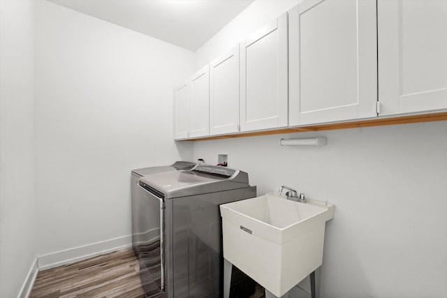 laundry room featuring cabinets, light wood-type flooring, washer and clothes dryer, and sink