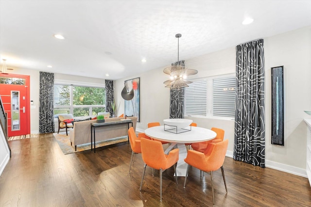 dining space featuring dark wood-type flooring and an inviting chandelier