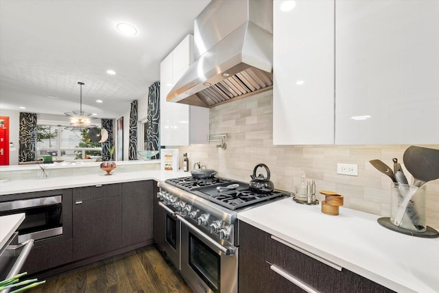 kitchen with wall chimney exhaust hood, dark wood-type flooring, double oven range, decorative backsplash, and white cabinets