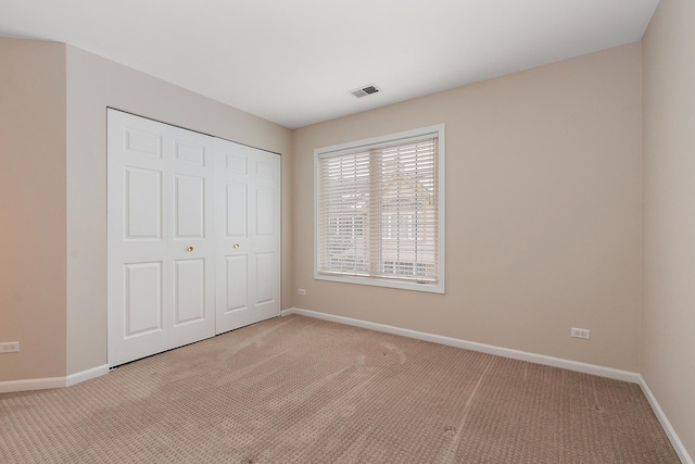 unfurnished bedroom with light colored carpet and a closet