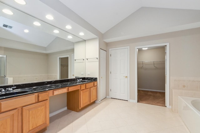 bathroom with lofted ceiling, a bathing tub, tile patterned flooring, and vanity