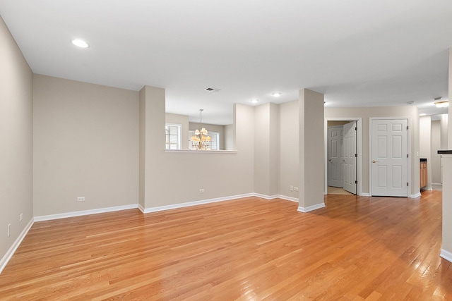 spare room featuring an inviting chandelier and light hardwood / wood-style flooring