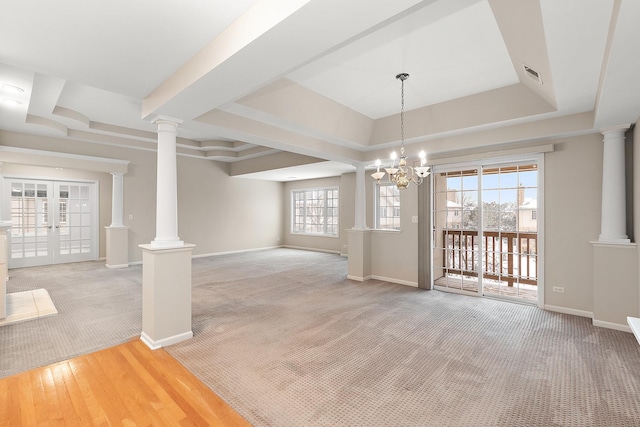 unfurnished dining area featuring french doors, an inviting chandelier, a raised ceiling, and carpet flooring