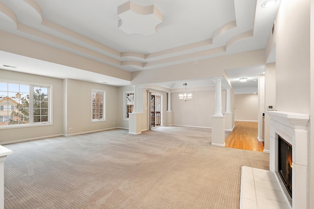 unfurnished living room with an inviting chandelier, a raised ceiling, and a fireplace