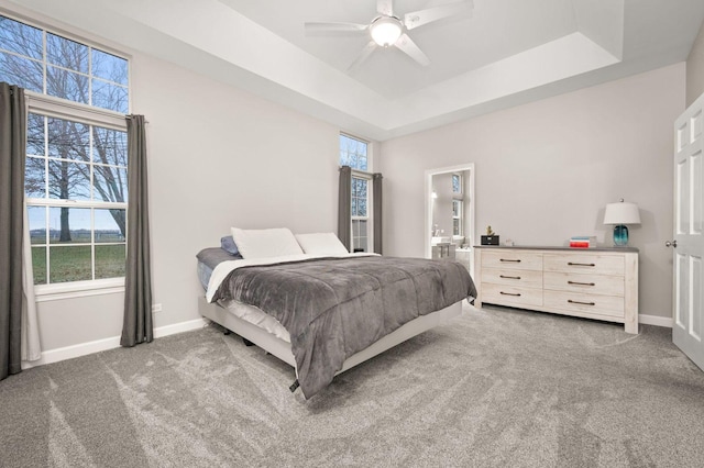 bedroom with a raised ceiling, ceiling fan, and dark colored carpet