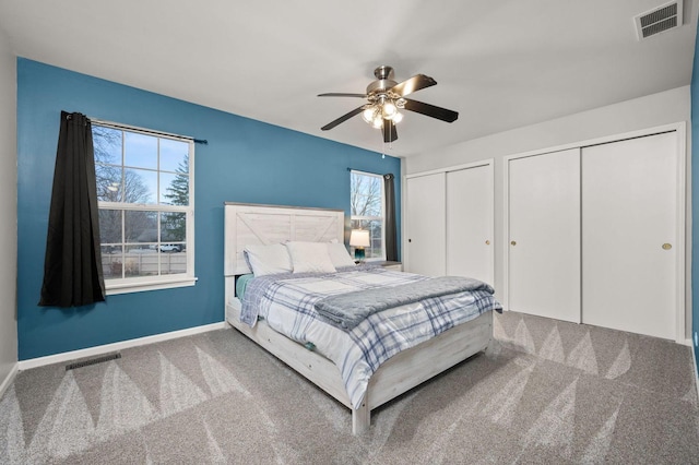 bedroom featuring two closets, ceiling fan, and carpet