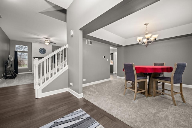 dining space featuring ceiling fan with notable chandelier and dark wood-type flooring