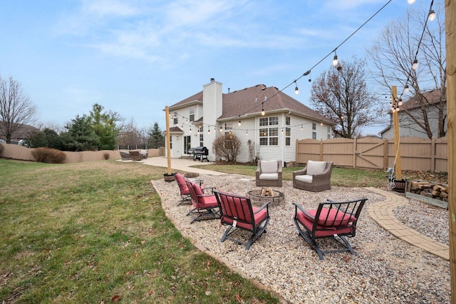 rear view of house with a patio, a yard, and an outdoor living space with a fire pit