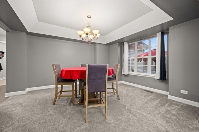 carpeted dining area with an inviting chandelier and a raised ceiling