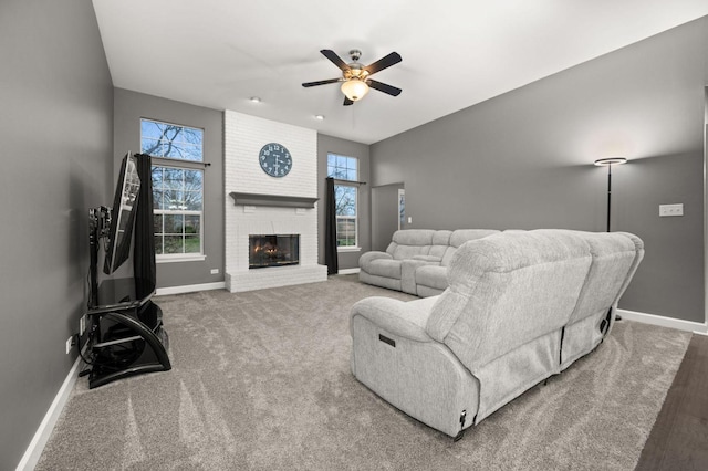 carpeted living room with ceiling fan and a brick fireplace