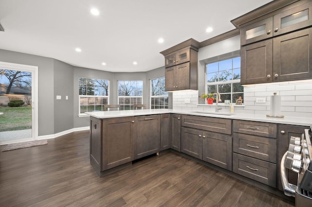 kitchen featuring tasteful backsplash, dark hardwood / wood-style floors, kitchen peninsula, and sink