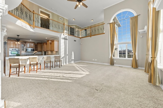 interior space featuring a high ceiling, light carpet, stainless steel appliances, backsplash, and ceiling fan