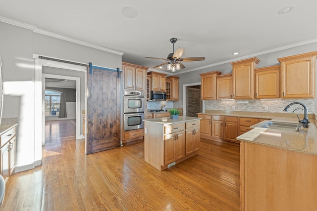 kitchen featuring tasteful backsplash, a barn door, a center island, sink, and stainless steel appliances