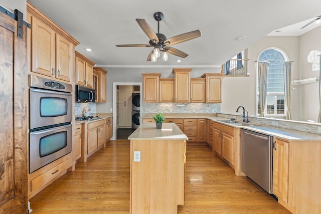 kitchen with a center island, decorative backsplash, stacked washer and dryer, stainless steel appliances, and light brown cabinetry