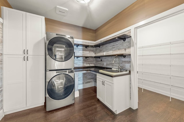 washroom with stacked washer and dryer, sink, and cabinets