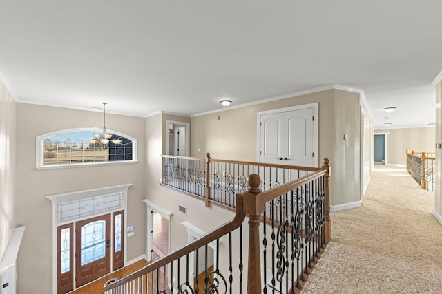 hallway with ornamental molding, carpet flooring, and a notable chandelier