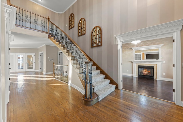 entrance foyer with french doors, ornamental molding, a fireplace, and hardwood / wood-style flooring