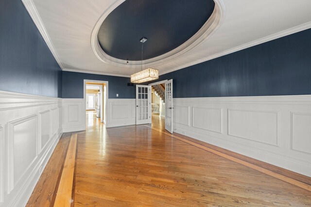 empty room featuring a raised ceiling, ornamental molding, and hardwood / wood-style flooring