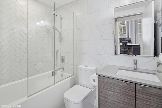 full bathroom featuring tile walls, shower / bath combination with glass door, vanity, and toilet