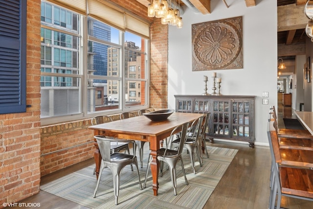 dining space with beam ceiling, dark hardwood / wood-style flooring, a notable chandelier, and brick wall