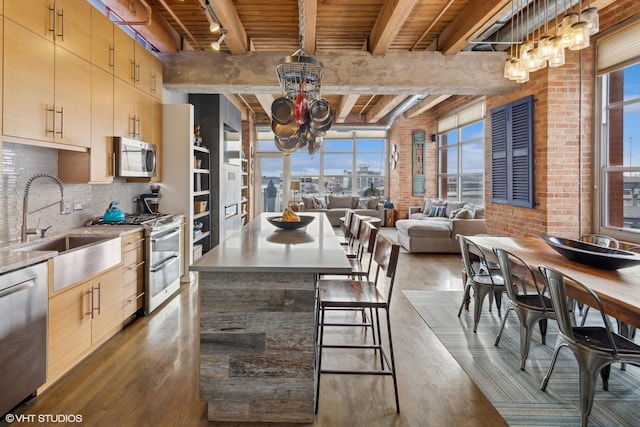 kitchen with wood ceiling, appliances with stainless steel finishes, brick wall, a notable chandelier, and beam ceiling