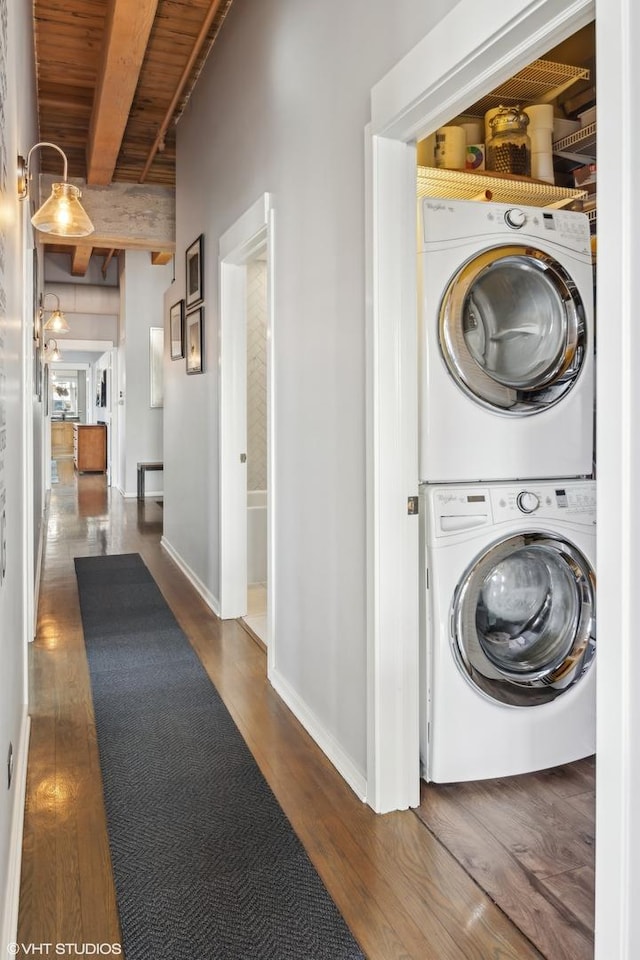 laundry room with dark wood-type flooring, wooden ceiling, and stacked washer and dryer