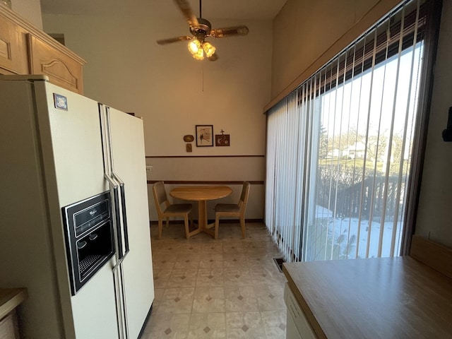 kitchen with ceiling fan, white fridge with ice dispenser, and light brown cabinets