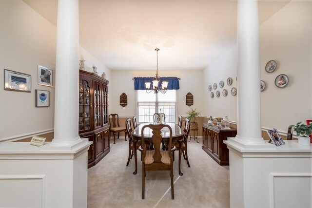 dining space featuring a chandelier, light colored carpet, and ornate columns