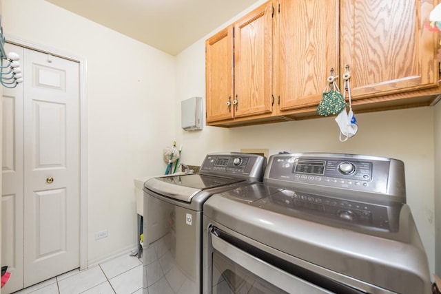 laundry room featuring washing machine and dryer, light tile patterned floors, and cabinets