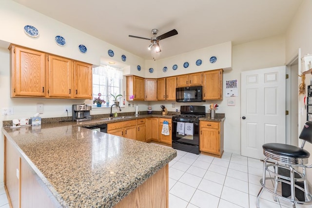 kitchen featuring kitchen peninsula, black appliances, sink, and stone counters