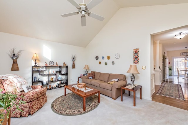 carpeted living room featuring ceiling fan with notable chandelier and high vaulted ceiling