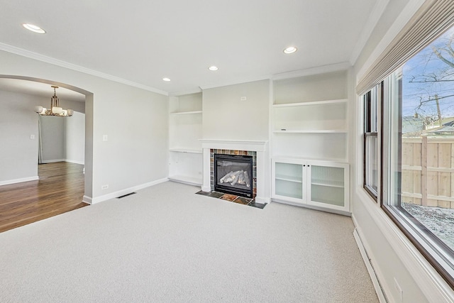 unfurnished living room featuring carpet, a notable chandelier, and ornamental molding