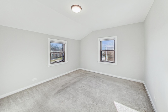 carpeted spare room featuring a healthy amount of sunlight and lofted ceiling