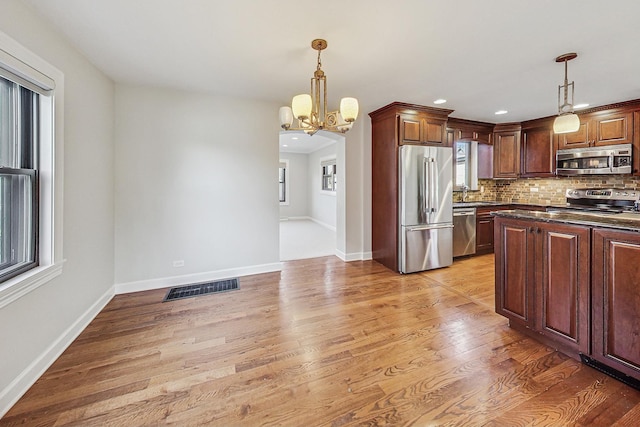 kitchen featuring pendant lighting, stainless steel appliances, an inviting chandelier, and tasteful backsplash