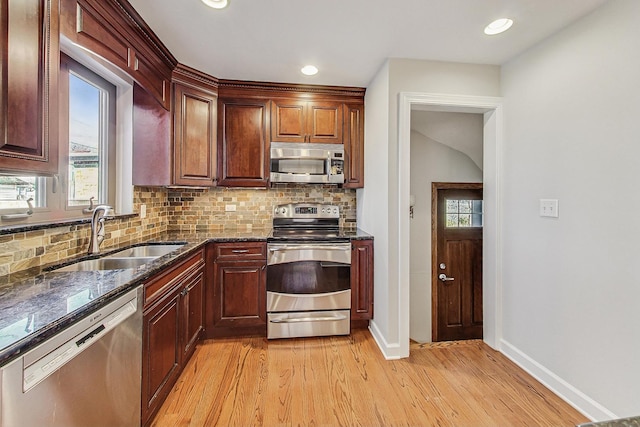 kitchen featuring dark stone counters, sink, light wood-type flooring, tasteful backsplash, and stainless steel appliances