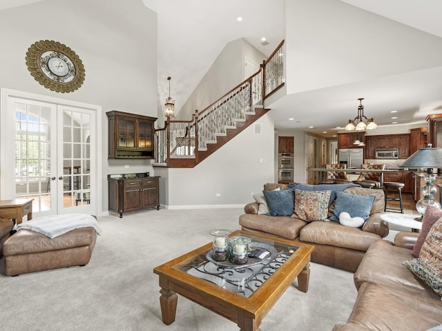 carpeted living room with french doors, an inviting chandelier, and a high ceiling