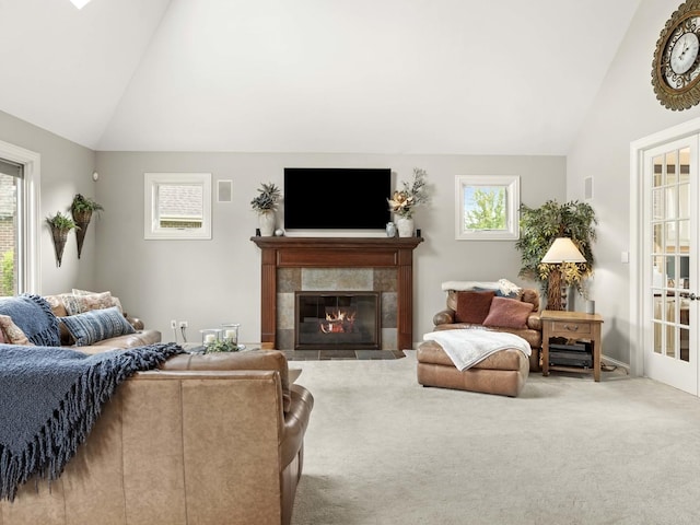 living room featuring carpet, a tile fireplace, and vaulted ceiling