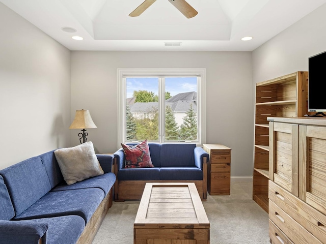 living room featuring a tray ceiling, ceiling fan, and light colored carpet