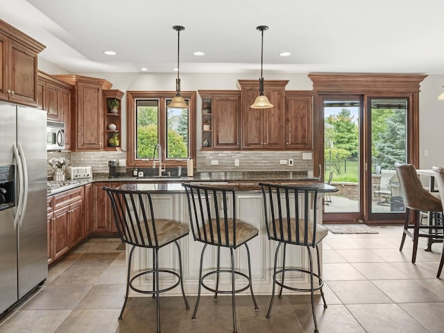 kitchen featuring a center island, a kitchen breakfast bar, stainless steel fridge, plenty of natural light, and decorative light fixtures