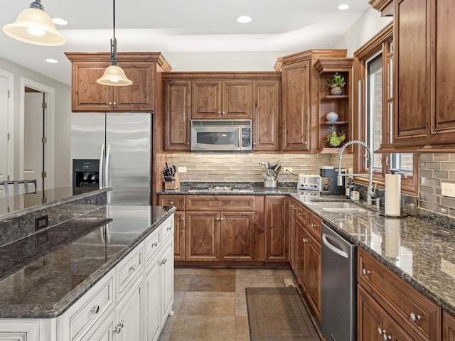 kitchen featuring sink, stainless steel appliances, dark stone counters, decorative light fixtures, and decorative backsplash