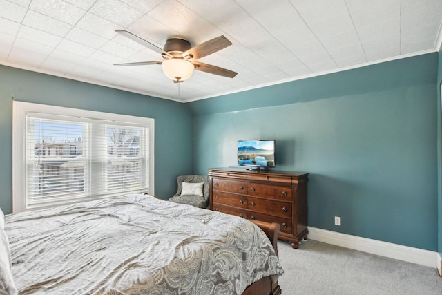 bedroom with a ceiling fan, baseboards, carpet, and crown molding