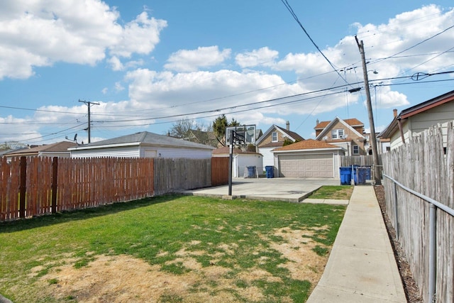 view of yard featuring a detached garage, a fenced backyard, an outdoor structure, and a residential view